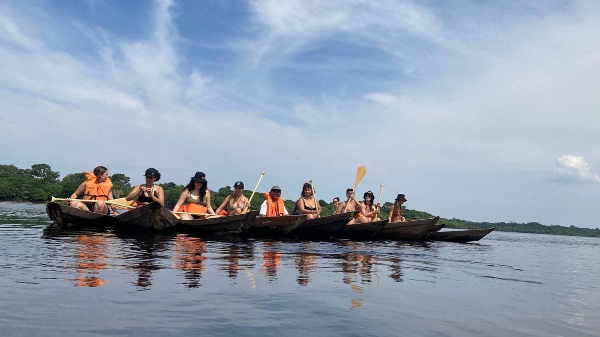 Canoas com viajantes remando num rio da Amazônia