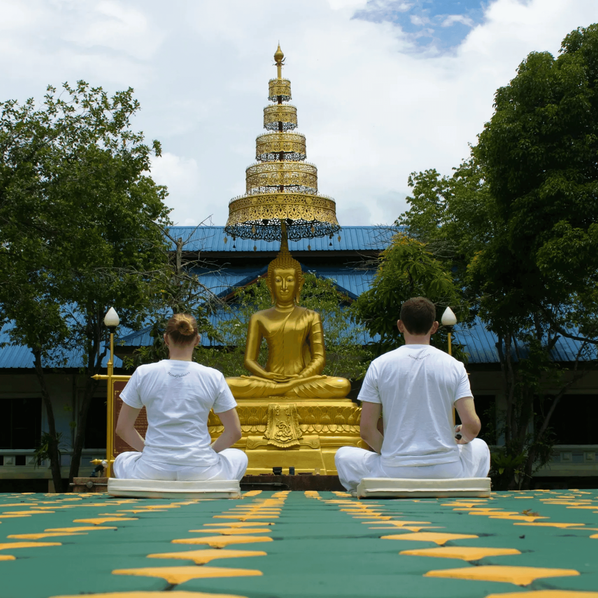 Pessoas em meditação diante de uma imagem de Buda